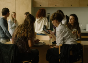 Group of young people sitting around a table looking at a tablet together